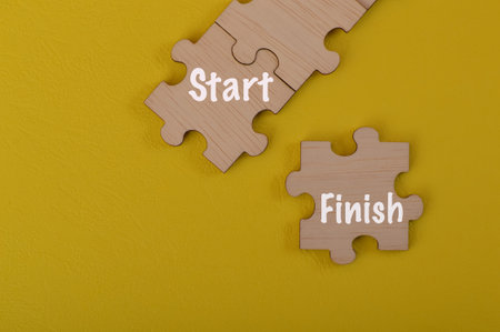 Wooden jigsaw puzzle with text START and FINISH.の写真素材