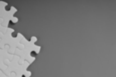 Blurred image of puzzle piece with copy space for the text. Black and white puzzles.