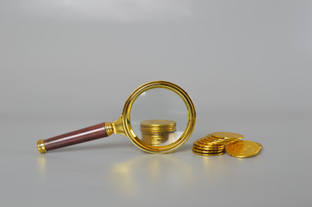 Golden coins and magnifying glass. Inflation, tax, cash flow and financial conceptの写真素材
