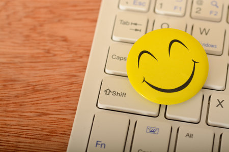 A happy face emoticon on a laptop keyboard represents concepts of customer service evaluation and satisfaction surveys.の写真素材