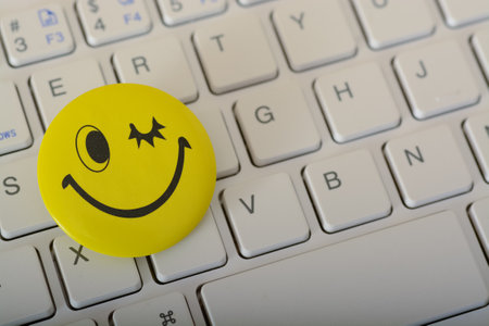A happy face emoticon on a laptop keyboard represents concepts of customer service evaluation and satisfaction surveys.の写真素材