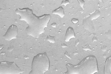 Water droplets on a textured grey background. A glass backdrop covered with water droplets,...