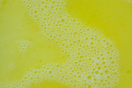 A close-up view of bubbles on yellow washing liquid, creating a bubbly background.の写真素材