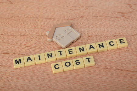 Toy house model with text MAINTENANCE COST.Housing cost concept
