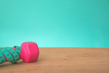 Green measuring tape and dumbbell isolated on a green background.の写真素材