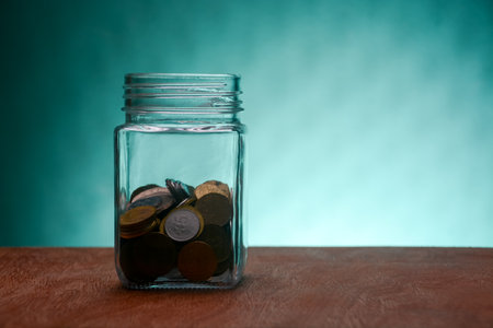 Stack of coins in a glass jar isolated on a green background.money saving investment concept.の写真素材