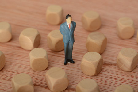 The businessman, deep in thought and surrounded by wooden blocks, pondered the problem and the challenge of development, searching for a solution for the companyの写真素材
