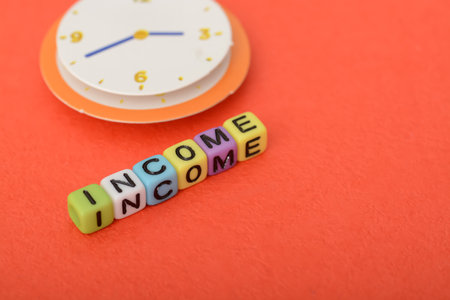 Alphabet beads with text INCOME. Income is money or value that an individual or business entity receives in exchange for providing a good or service or through investing capital.の写真素材
