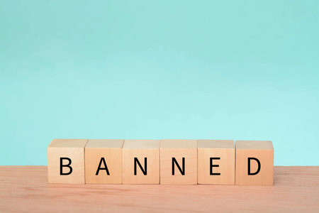 Wooden block with text BANNED. A ban refers to a formal or official prohibition or restriction on a particular activity, action, item, or person. It is an authoritative decision made by a governmentの写真素材