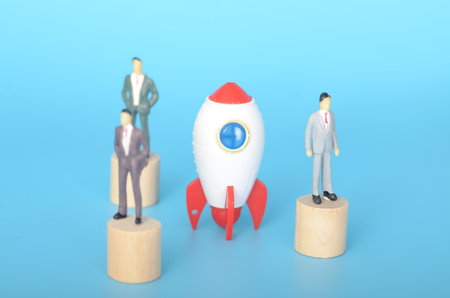 a miniature figure representing an individual or team embarking on a global venture, symbolized by the globe, using the power of technology, represented by the rocket.の写真素材