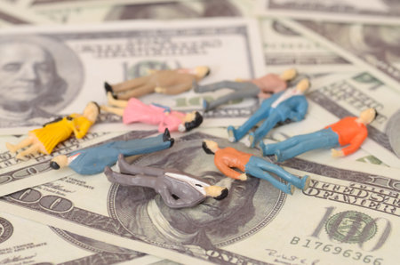 The image of businessmen collapsing on a pile of money banknotes highlights the extreme stress and financial strain faced in high-stakes business environments.の写真素材