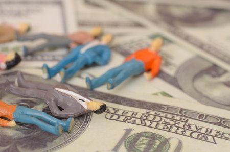 a businessman collapsing onto a pile of banknotes starkly illustrates the peril of financial mismanagement and the overwhelming stress that can accompany economic failure.の写真素材