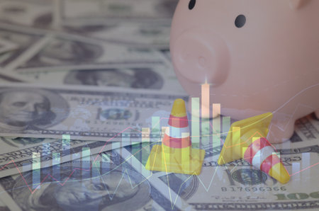 a piggy bank surrounded by dollar bills and traffic cones, symbolizing the potential challenges and obstacles that can arise in financial planning and saving.の写真素材
