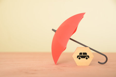 The image of an umbrella protecting a car represents the importance of car insurance.の写真素材
