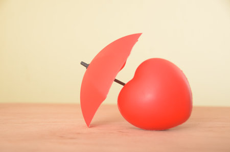 The red heart, partially shielded by a fragmented umbrella, symbolizes the fragility of love, protection shattered in the face of adversity, leaving behind remnants of what once offered comfort.の写真素材