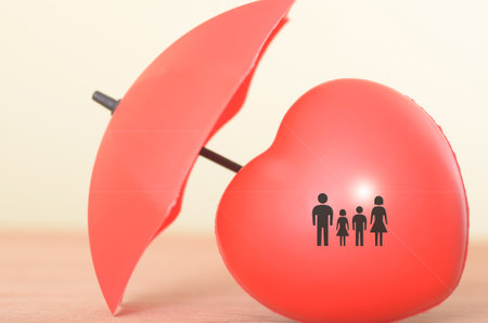 The image of a family symbol protected by an umbrella represents the importance of family life insurance.の写真素材