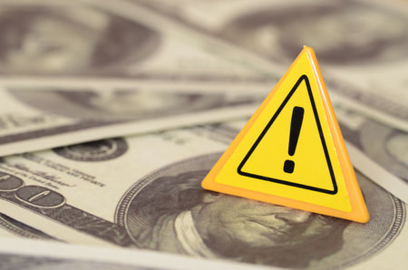 The cautionary triangle sign amidst a sea of dollar bills warns of the potential pitfalls and risks associated with financial gain.の写真素材