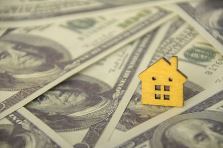 The juxtaposition of the house and the money suggests the significant financial investment required...