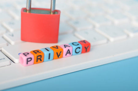 a red padlock standing tall over a row of letter blocks spelling out "PRIVACY," symbolizing the concept of data protection and online privacy.の写真素材