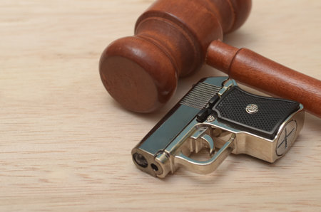 the juxtaposition of law and force, symbolized by the gun and judge's gavel, representing the balance between power and justice in society.の写真素材