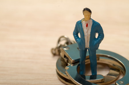 Caught Between Power and Consequences: The Businessman's Dilemma with Handcuffs and Warningsの写真素材