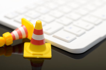 Safety Precautions and Work Efficiency Concept: Traffic Cones with Keyboard on Workspace