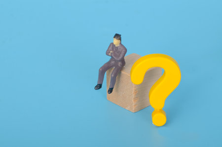 Confused Businessman Sitting and Thinking with a Question Mark Symbolizing Decision-Making Challengesの写真素材