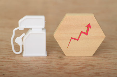 Symbolizing Increasing Fuel Costs: Mini Gas Pump and Red Arrow Conceptの写真素材