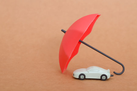 Red Umbrella Shielding a Toy Car: A Symbol of Protectionの写真素材