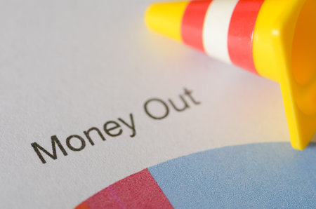 Money Out: Budget Worksheet with Caution Symbol Highlighting Financial Risksの写真素材
