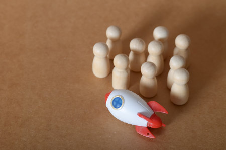 Teamwork and Innovation Concept with Wooden Peg Dolls and Toy Rocket