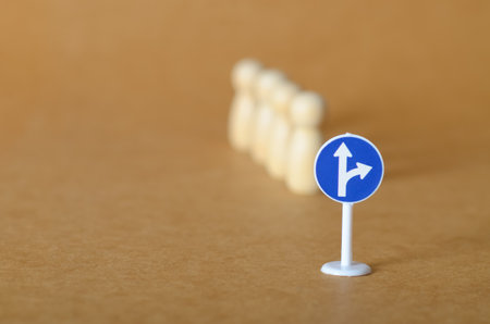 Pathway to Decision: Road Sign with Directional Arrows and Wooden Peg Dolls Representing a Group