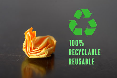 100% Recyclable and Reusable Concept Featuring Green Recycling Icon and Crumpled Orange Item