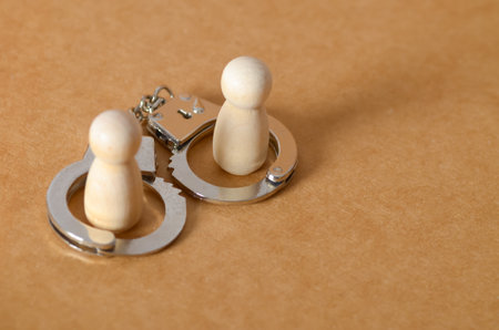 Concept of Confinement: Wooden Doll Trapped in Metal Handcuff Ring