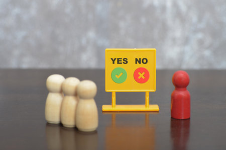Voting Concept with Wooden Figures and Yes/No Sign Symbolizing Public Opinionの写真素材