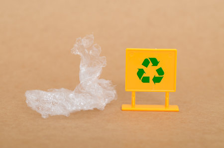 Recycling Plastic Waste: Clear Plastic and Green Symbol on Yellow Sign