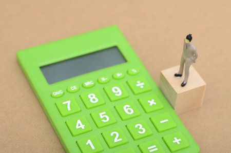 Businessman Looking at Calculator and Thinking: Concept of Financial Planning, Budgeting, and Decision Makingの写真素材