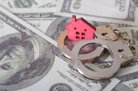 Miniature Red House in Handcuffs on Dollar Bills â€“ Concept of Property Financial Crisis and...