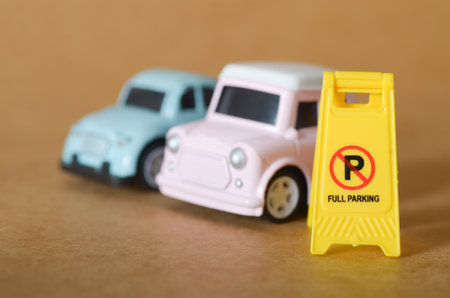 Full Parking Concept with Yellow Sign and Miniature Cars in Foregroundの写真素材