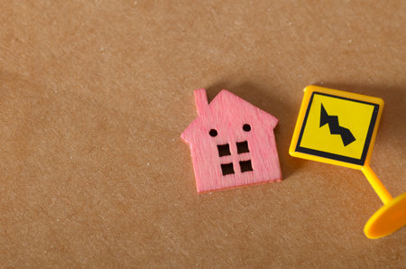 Tiny Pink House and Hazard Sign Symbolizing Real Estate Risk and Property Instability