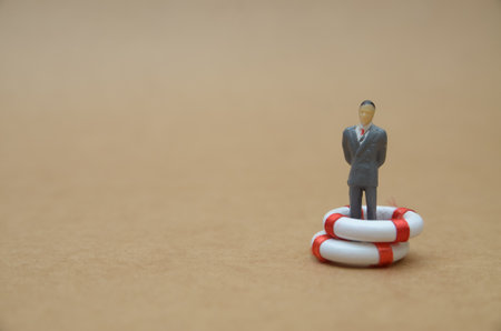 Business Stability Concept â€“ Figurine in Life Buoy Representing Corporate Safety Net and...