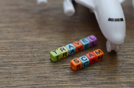 Travel Scam Concept â Airplane and Alphabet Beads on Wooden Table Symbolizing Tourism Deceptionの写真素材