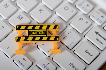 Digital Caution: Miniature Barrier on Keyboard Symbolizing Online Security and Cyber Threats.の写真素材