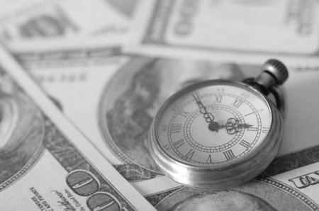 The Timeless Adage: A vintage pocket watch on hundred-dollar bills powerfully illustrating that time is money.の写真素材