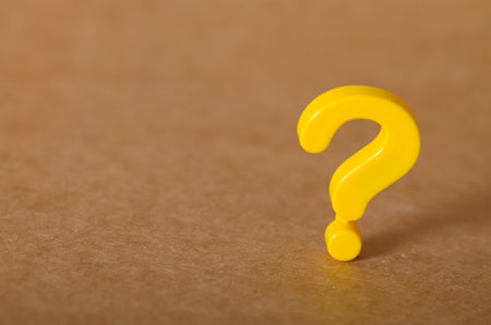 A bold, yellow question mark on a brown background, symbolizing inquiry, problems, and the search for solutions.の写真素材