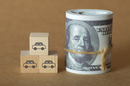 The High Cost of Vehicle Ownership: A Roll of Hundred-Dollar Bills Symbolizing the Financial Investment Required for Automobiles.の写真素材