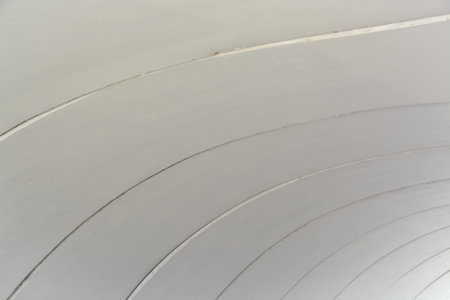 A close-up of a curved, off-white surface with parallel recessed lines, creating a clean, geometric...