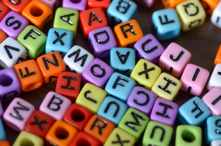 A vibrant, chaotic pile of colorful, square alphabet beads, symbolizing the foundational elements of...