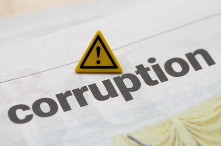 A warning sign over a corruption headline on a newspaper emphasizes the urgent danger and serious...