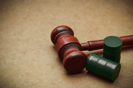 A judge's gavel beside miniature green barrels symbolizes environmental justice and the legal reckoning against industrial contamination and corporate polluters.の写真素材